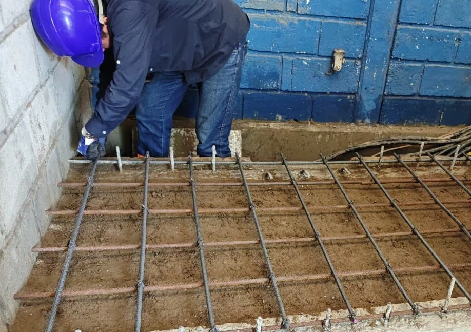 Personal técnico realizando el armado de parrilla de acero de refuerzo para la cimentación de una base de concreto industrial.