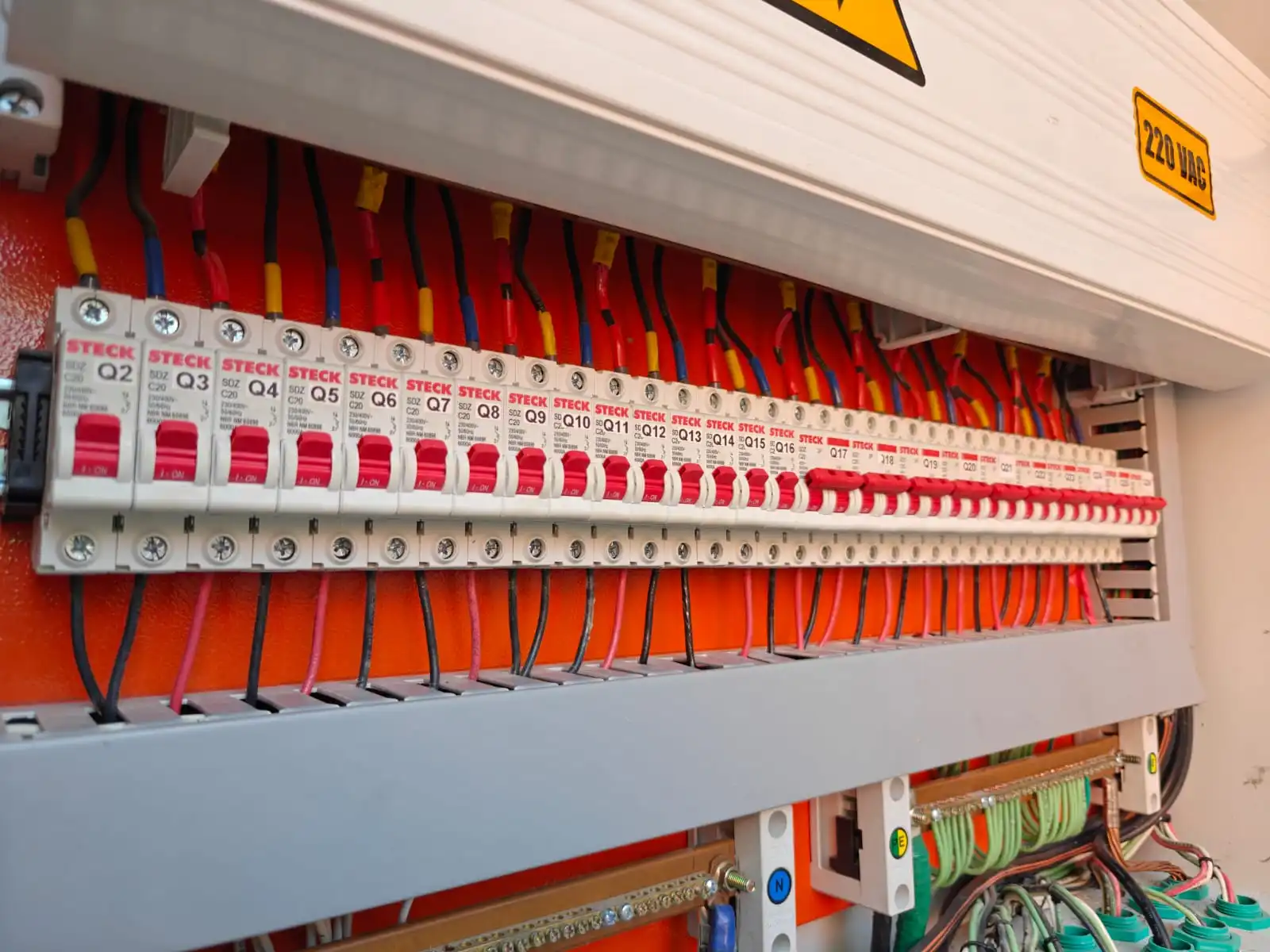 Instalación organizada de interruptores termomagnéticos en riel DIN con peinado de conductores y canaletas de protección para distribución eléctrica industrial.